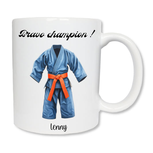Mug blanc en céramique  de 325 ml avec un dessin représentant un kimono de judo bleu avec une ceinture orange, et personnalisé avec un prénom, un texte. Cadeau pour coach, judoka