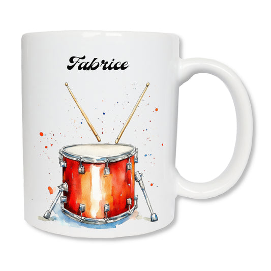 Mug blanc en céramique de 325 ml représentant un tambour orange et des baguettes, et personnalisé avec un prénom. Cadeau pour tambourineur.