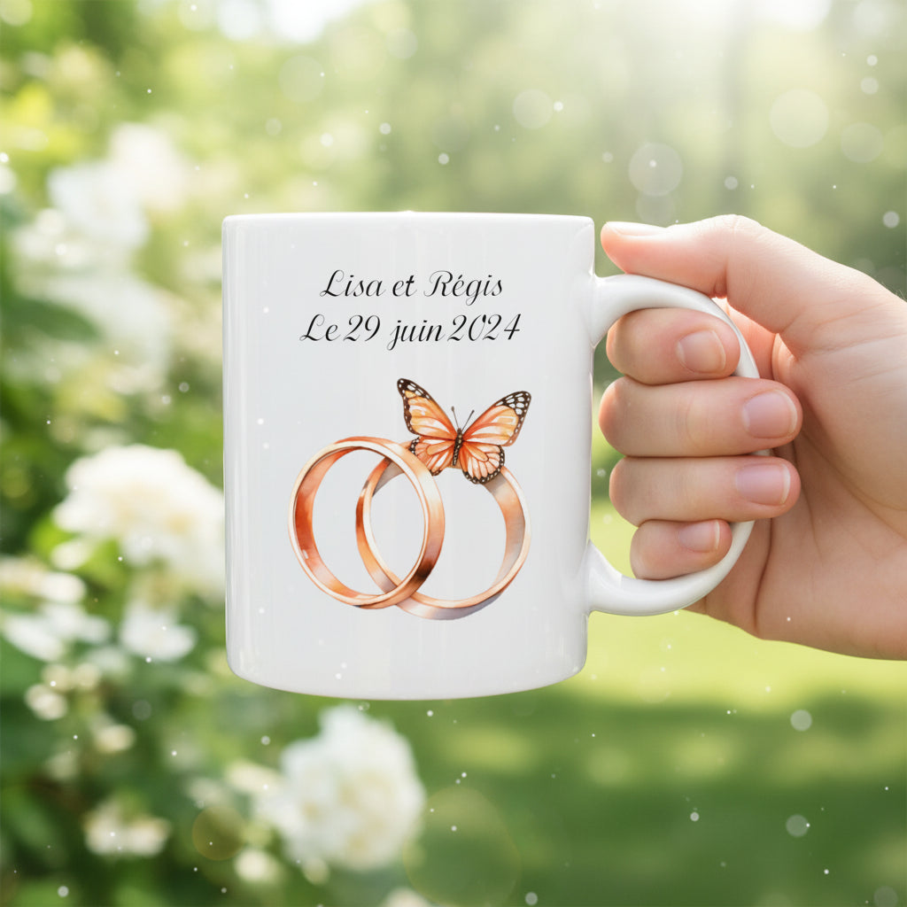 Mug personnalisé céramique 325 ml tenu avec une main avec motif alliances, date et prénom des jeunes mariés