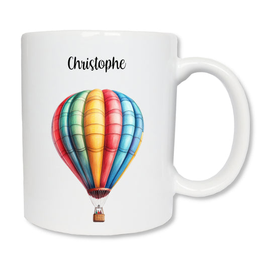 Mug blanc en céramique  de 325 ml avec une montgolfière multicolore, et personnalisé avec un prénom.