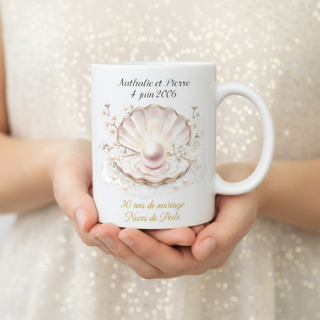 Mug personnalisé 30 ans de mariage Noces de Perle, tenu dans les mains avec illustration coquille et perle nacrée sur fond ivoire scintillant

