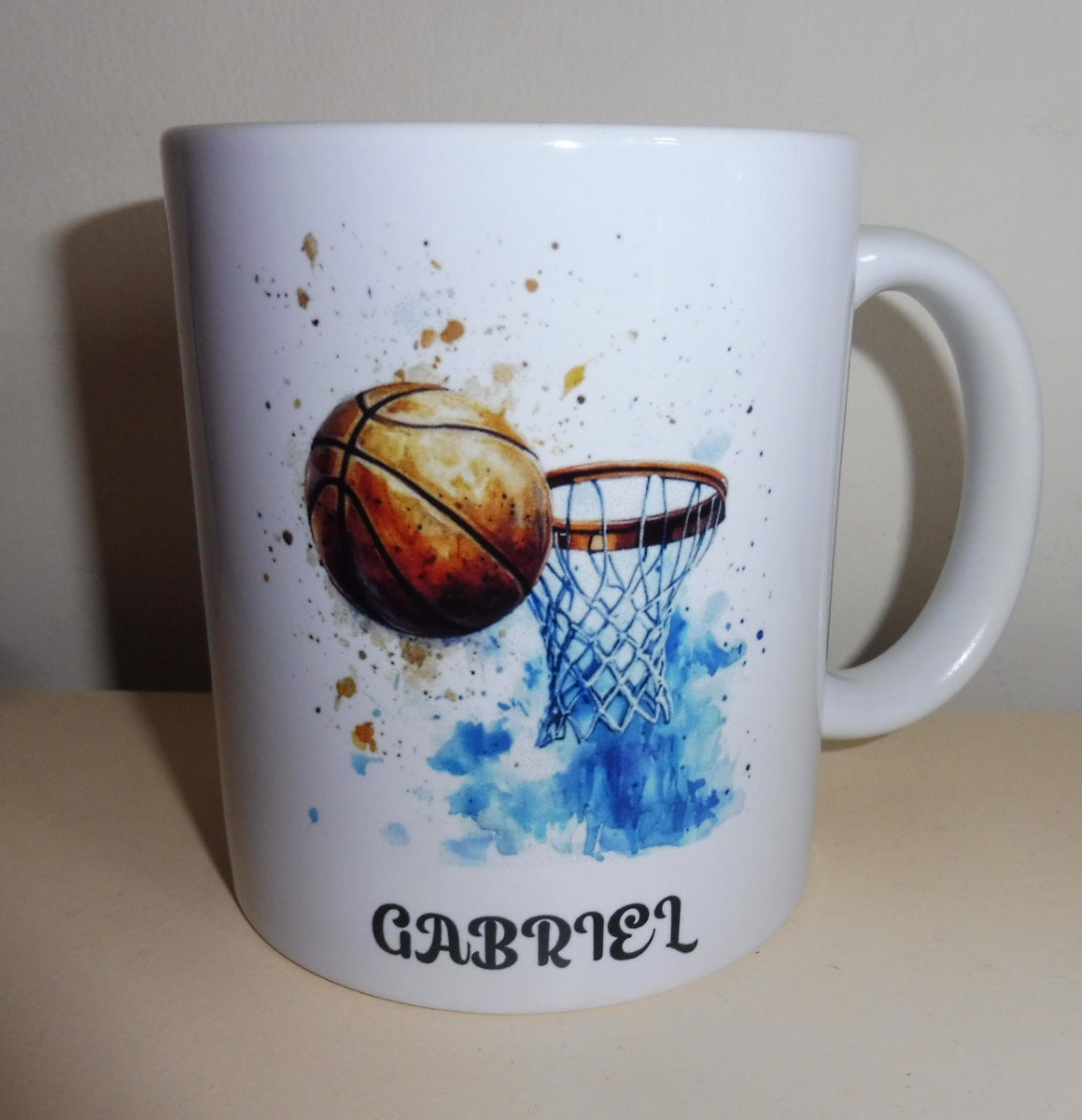 Mug blanc en céramique de 325 ml avec un ballon et un panier de basket, et personnalisé avec un prénom. Cadeau entraîneur
