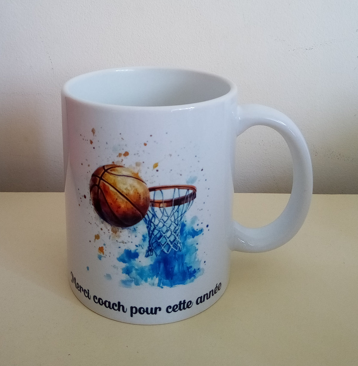 Mug blanc en céramique de 325 ml avec un ballon et un panier de basket, et personnalisé avec un prénom. 