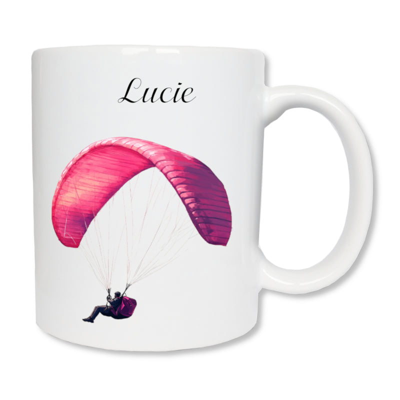 Mug blanc en céramique 325 ml avec  dessin représentant un homme qui fait du parapente de couleur rose, et personnalisé avec un prénom. Cadeau Noël pour parapentiste.