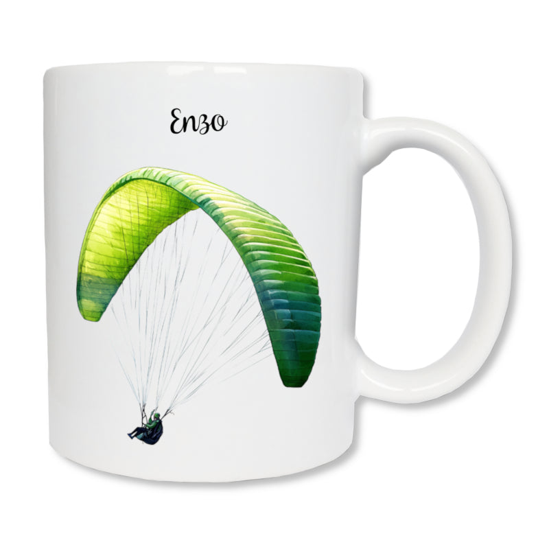 Mug blanc en céramique de 325 ml avec le dessin représentant un homme qui fait du parapente de couleur vert, et personnalisé avec un prénom. Cadeau pour parapentiste.