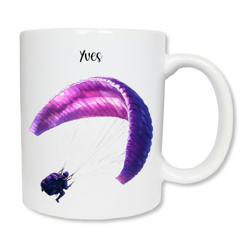 Mug blanc en céramique de 325 ml avec le dessin représentant un homme qui fait du parapente de couleur violet, et personnalisé avec un prénom. Cadeau pour parapentiste.