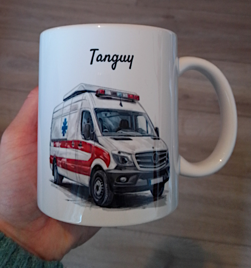Mug blanc en céramique de 325ml avec un camion ambulance,  et personnalisé avec un prénom. Cadeau pour ambulancier / ambulancière.