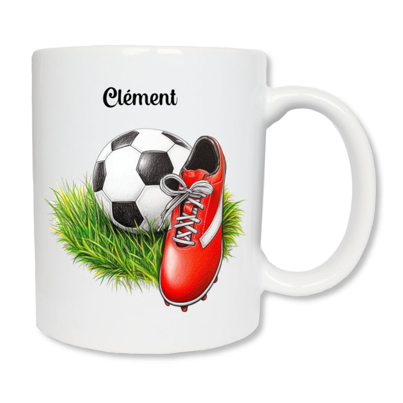 Mug blanc en céramique blanc de 325 ml imprimé avec un ballon et une chaussure de foot rougee posée sur de l'herbe et personnalisé avec un prénom - Cadeau enfant